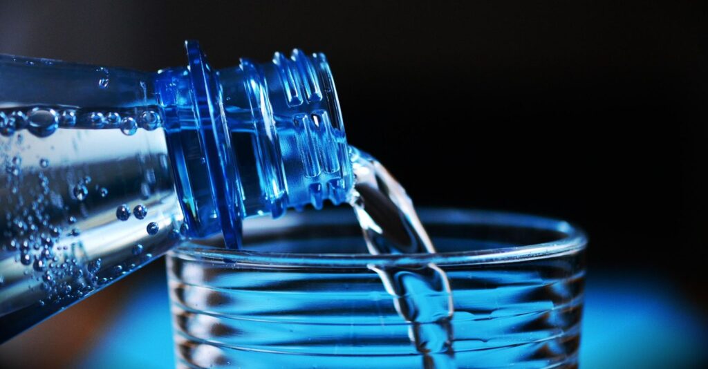 bottiglia di acqua minerale in plastica e bicchiere in vetro